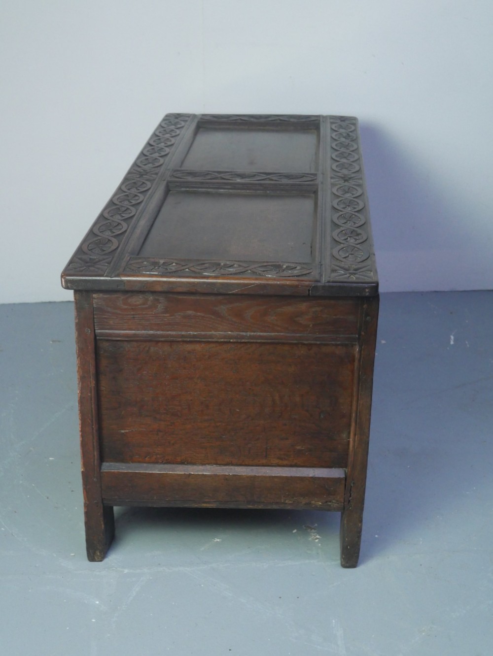A dark brown oak coffer featuring a carved fluted frieze, double front panels, and a hinged lid with carved geometric border details. View X