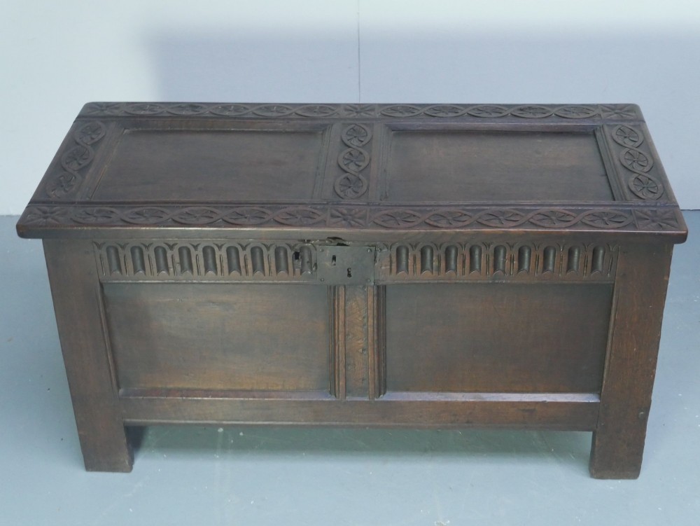 A dark brown oak coffer featuring a carved fluted frieze, double front panels, and a hinged lid with carved geometric border details. View XII