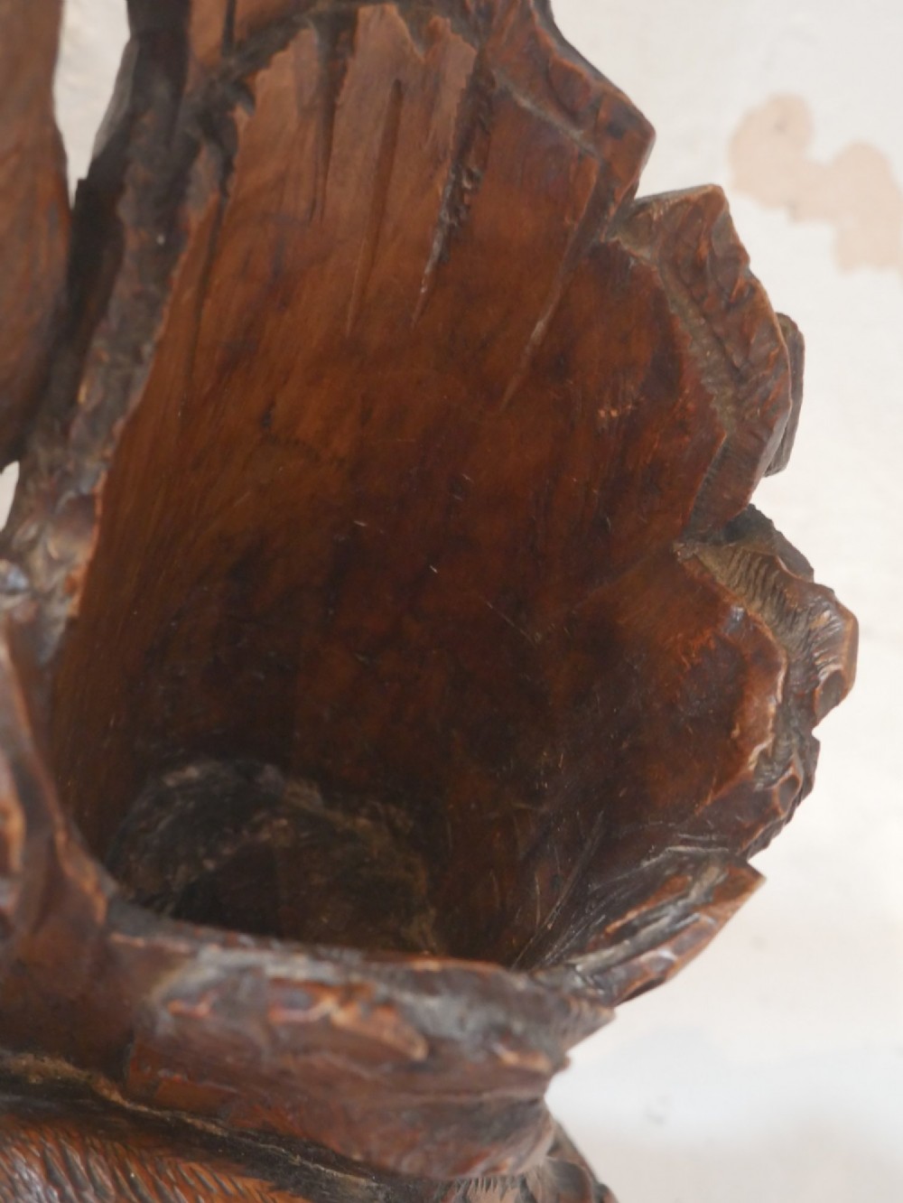 A hand-carved dark wood Black Forest sculpture depicting two mountain goats positioned beside a hollow tree stump on an oval base. View VI