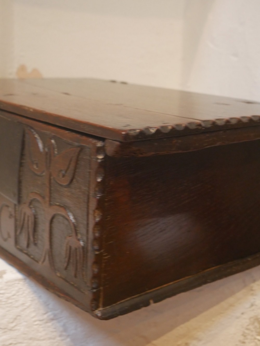 A dark carved oak box with hand-carved botanical motifs on the front panel and a central iron lockplate. View IV