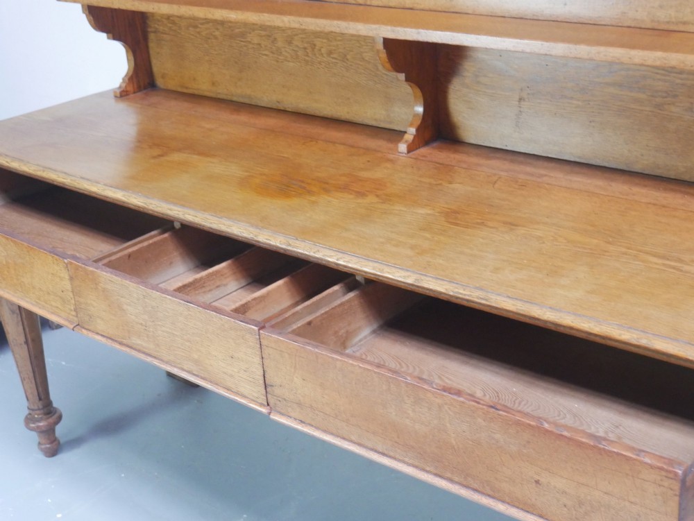 A large Victorian oak serving table featuring a raised back gallery shelf, frieze drawers, and turned front legs. View IV