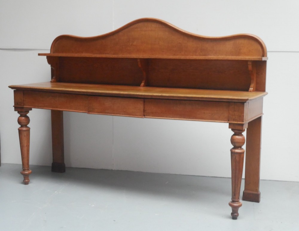 A large Victorian oak serving table featuring a raised back gallery shelf, frieze drawers, and turned front legs. View VIII