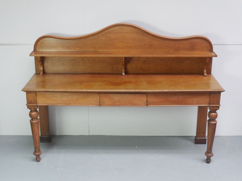 A large Victorian oak serving table featuring a raised back gallery shelf, frieze drawers, and turned front legs. View X