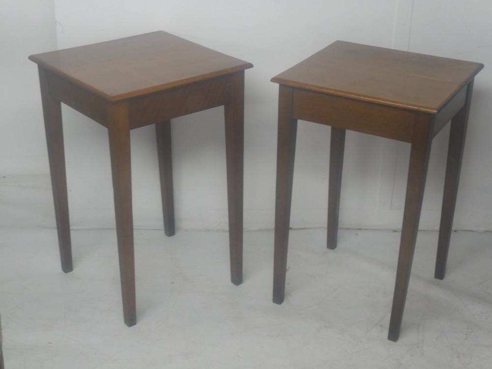 A pair of matching square wooden lamp tables made from warm brown oak, featuring square tops and simple tapered legs.
