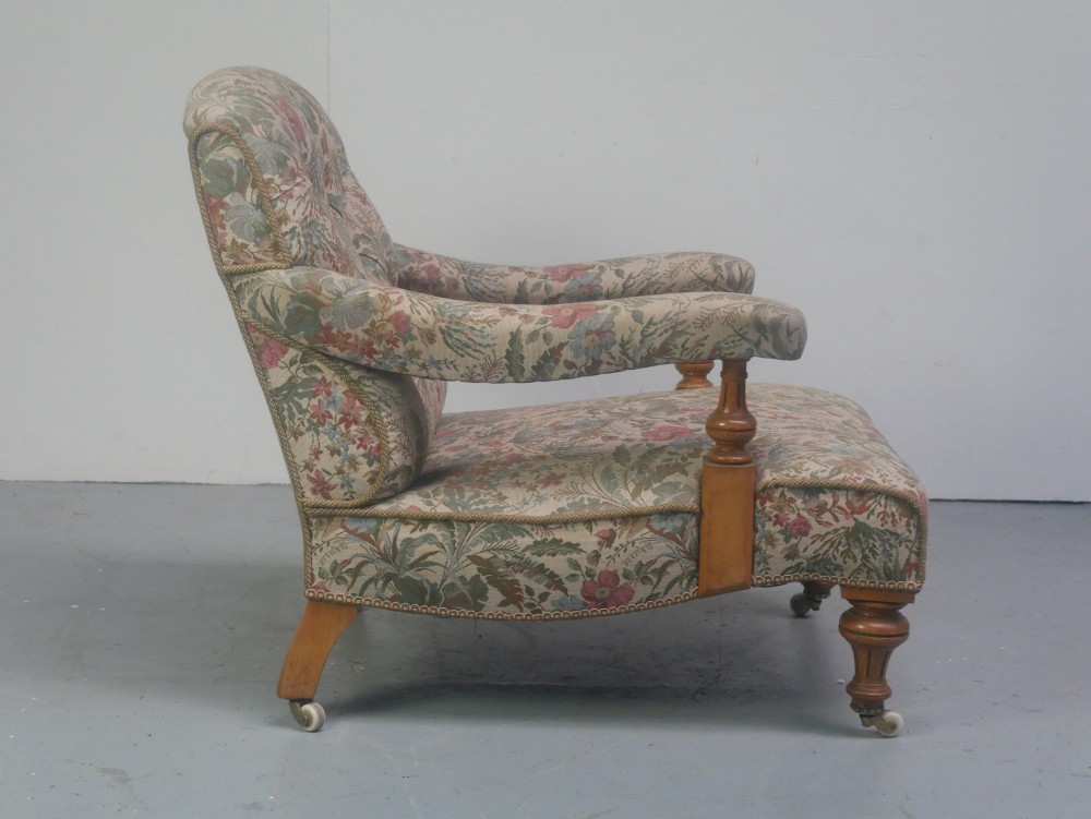 A 19th-century Howard style armchair with button-tufted floral tapestry upholstery, low padded arms, turned timber legs, and ceramic castors. View V