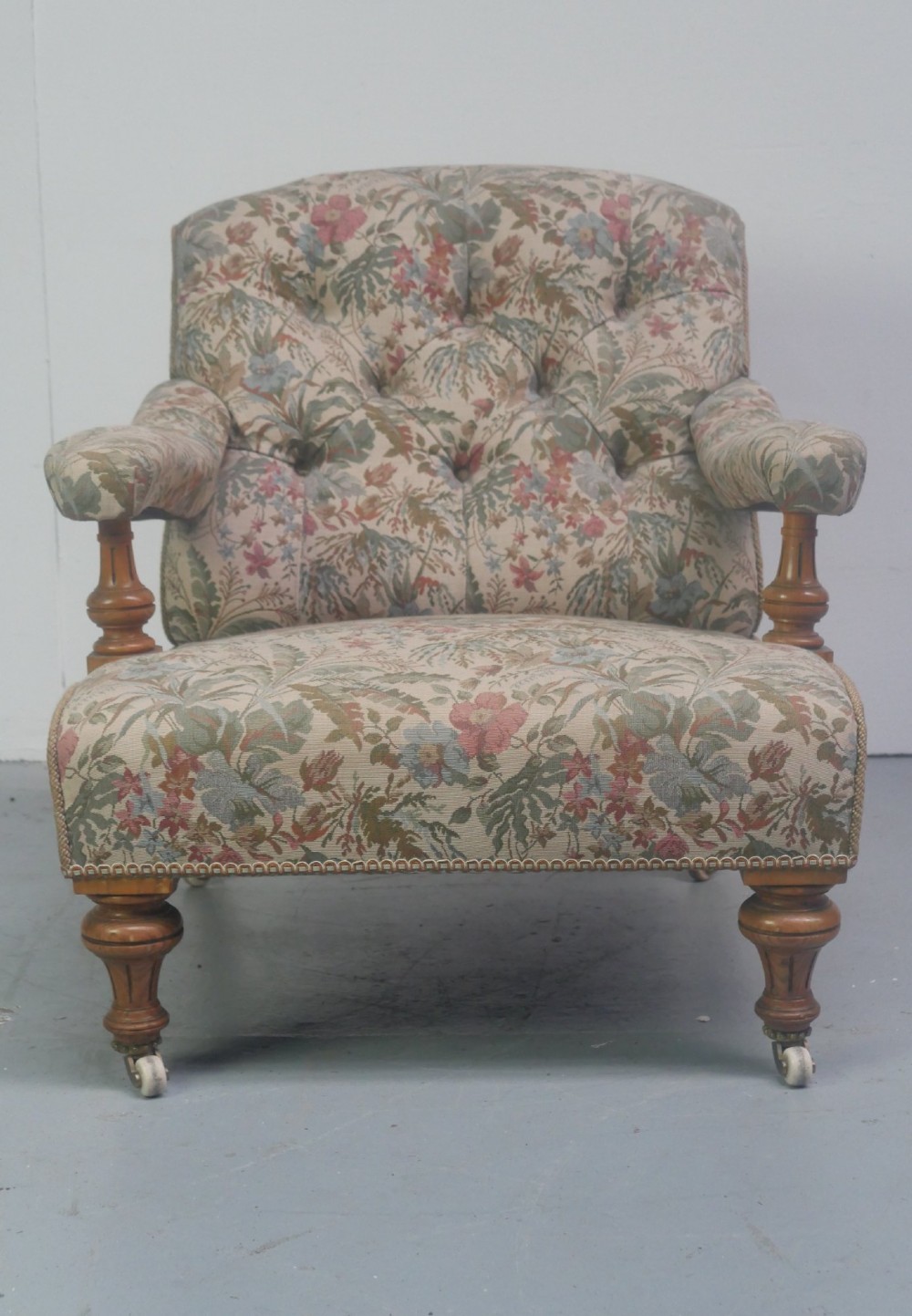 A 19th-century Howard style armchair with button-tufted floral tapestry upholstery, low padded arms, turned timber legs, and ceramic castors. View VI