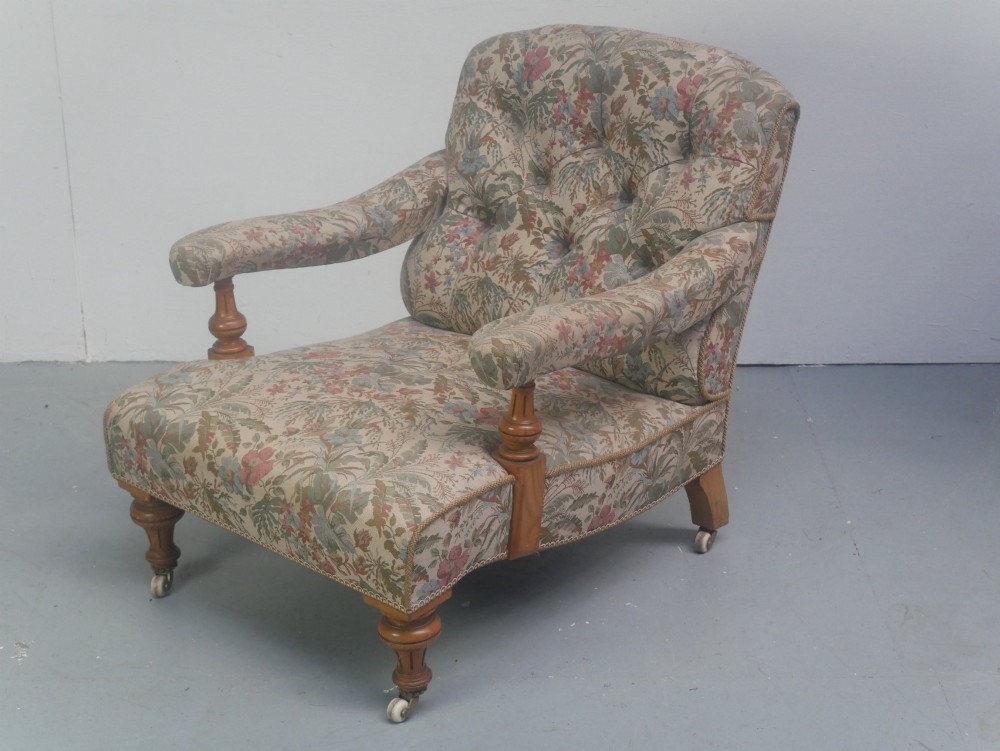 A 19th-century Howard style armchair with button-tufted floral tapestry upholstery, low padded arms, turned timber legs, and ceramic castors. View X
