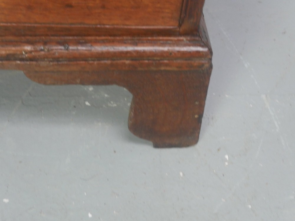 A Georgian oak chest of drawers featuring two short drawers over three long graduated drawers with brass swan-neck handles and bracket feet. View VI