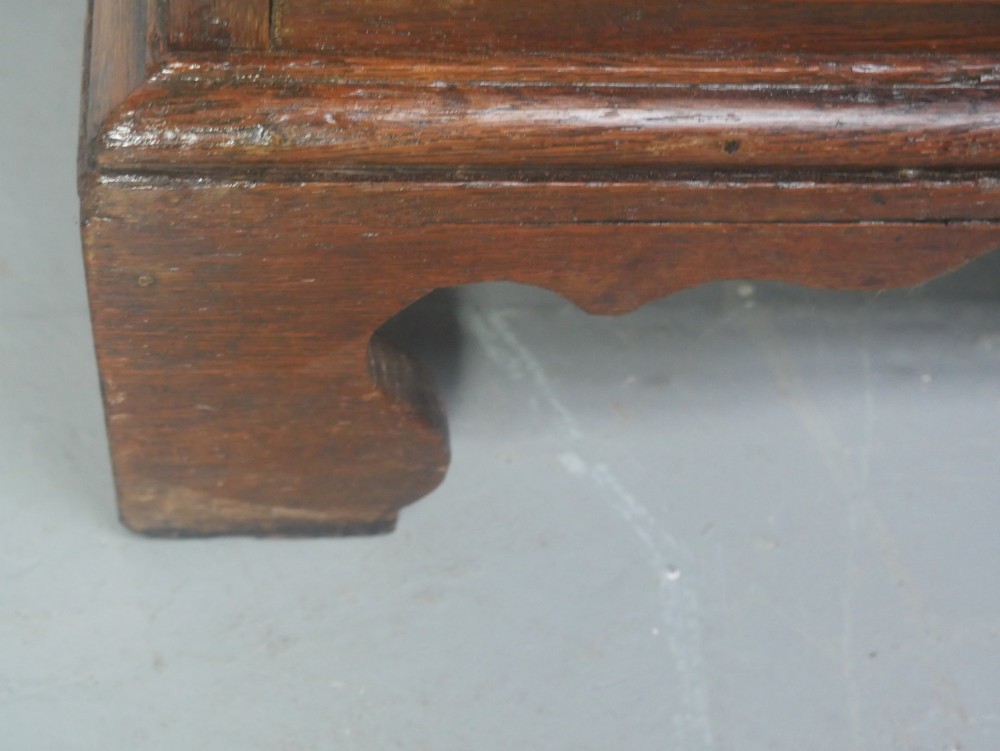 A Georgian oak chest of drawers featuring two short drawers over three long graduated drawers with brass swan-neck handles and bracket feet. View VII