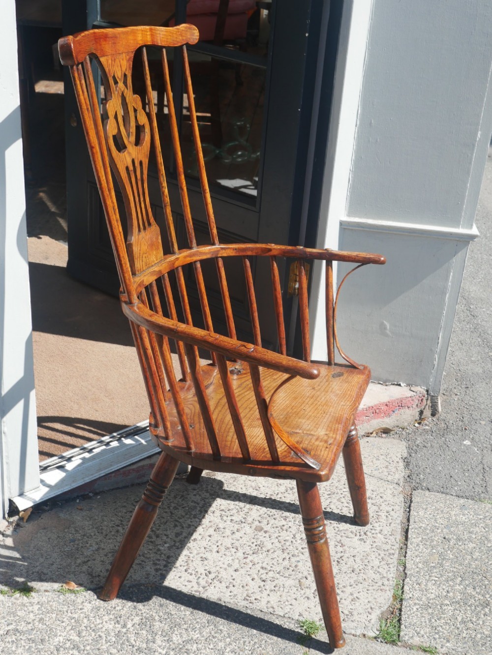 A Georgian comb back Windsor armchair featuring vertical wooden spindles, a pierced central splat, curved armrests, and turned legs. View IV