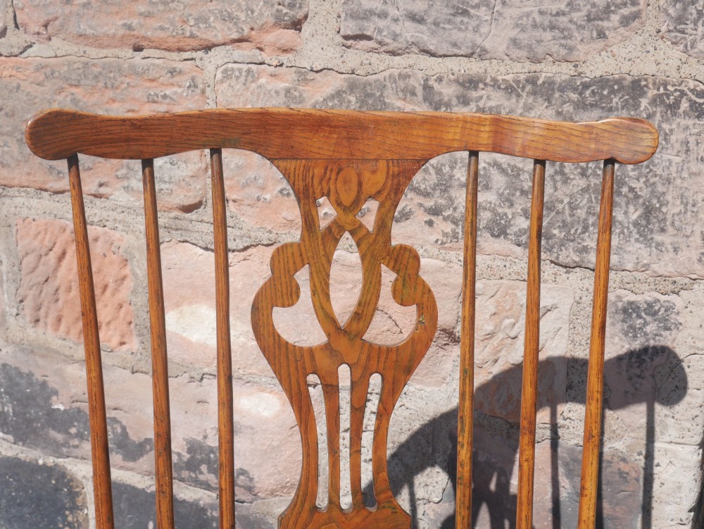 A Georgian comb back Windsor armchair featuring vertical wooden spindles, a pierced central splat, curved armrests, and turned legs. View V