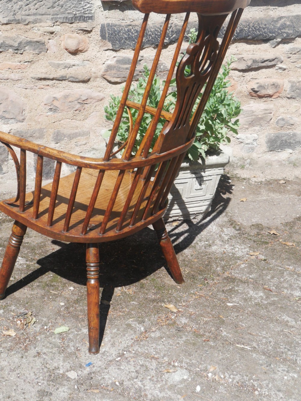 A Georgian comb back Windsor armchair featuring vertical wooden spindles, a pierced central splat, curved armrests, and turned legs. View VI