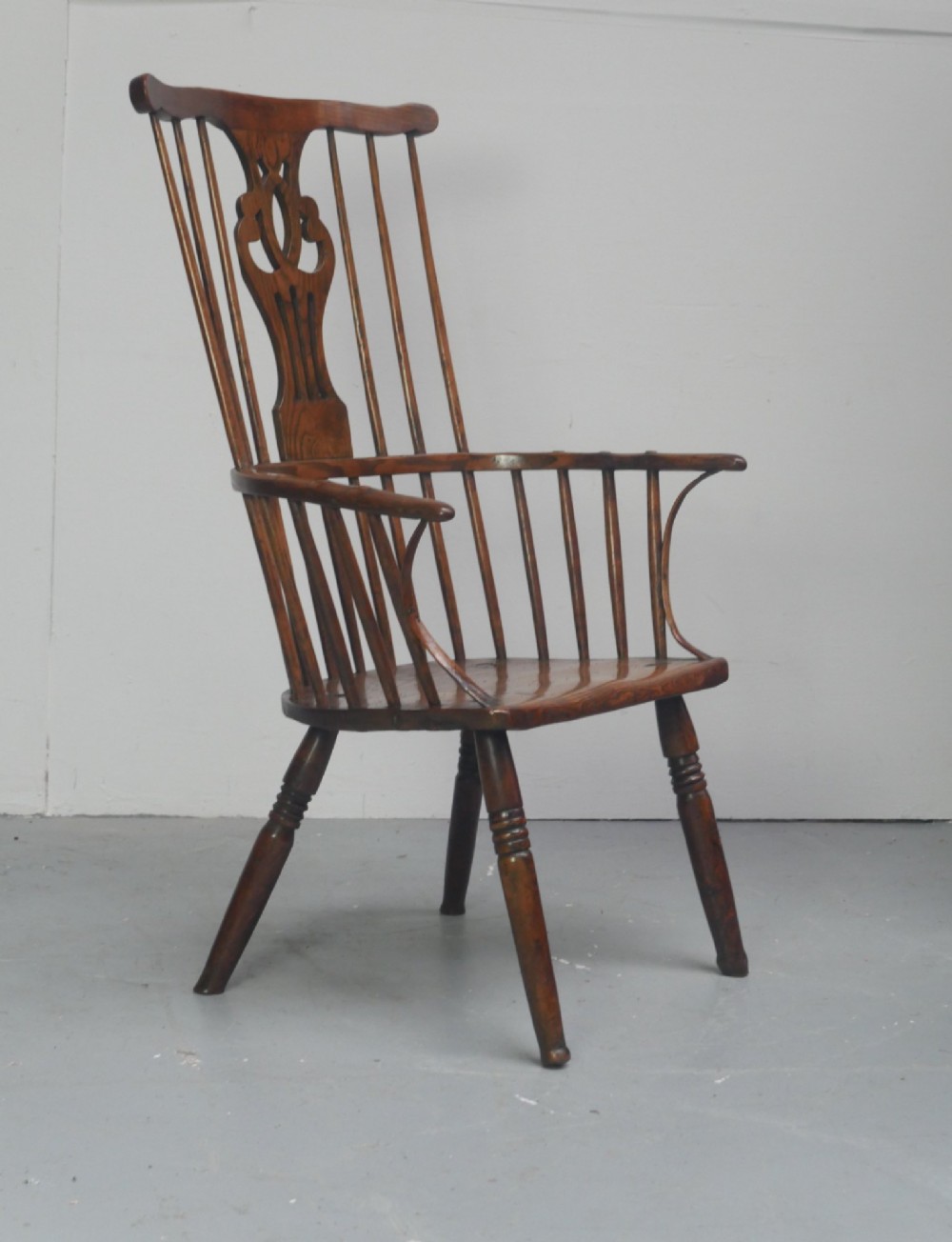 A Georgian comb back Windsor armchair featuring vertical wooden spindles, a pierced central splat, curved armrests, and turned legs. View VII