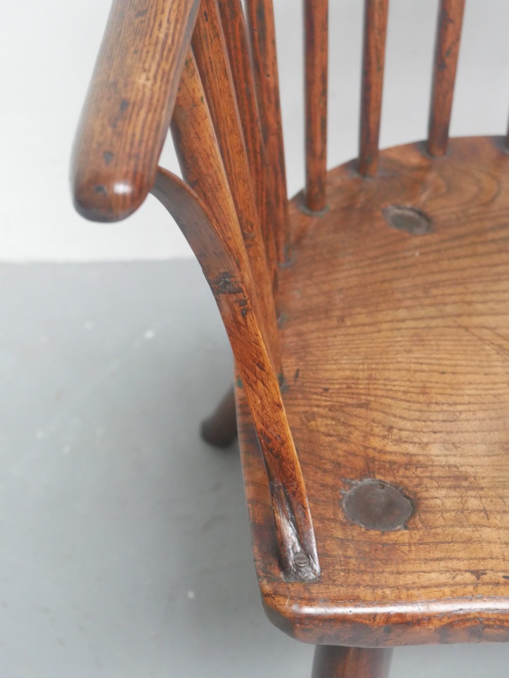 A Georgian comb back Windsor armchair featuring vertical wooden spindles, a pierced central splat, curved armrests, and turned legs. View X