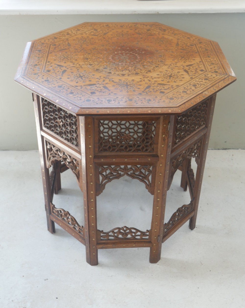 An octagonal Anglo-Indian dark wood side table decorated with intricate bone inlay patterns and pierced jali lattice arches.