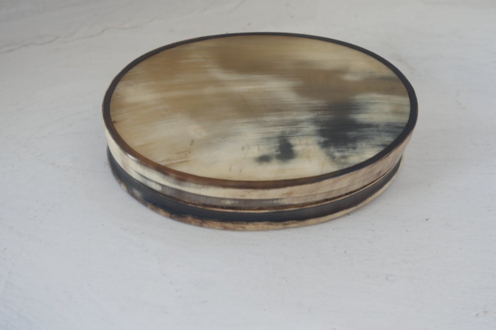 An oval antique snuff box crafted from polished natural horn showing variegated cream, amber, and dark brown mottling. View II