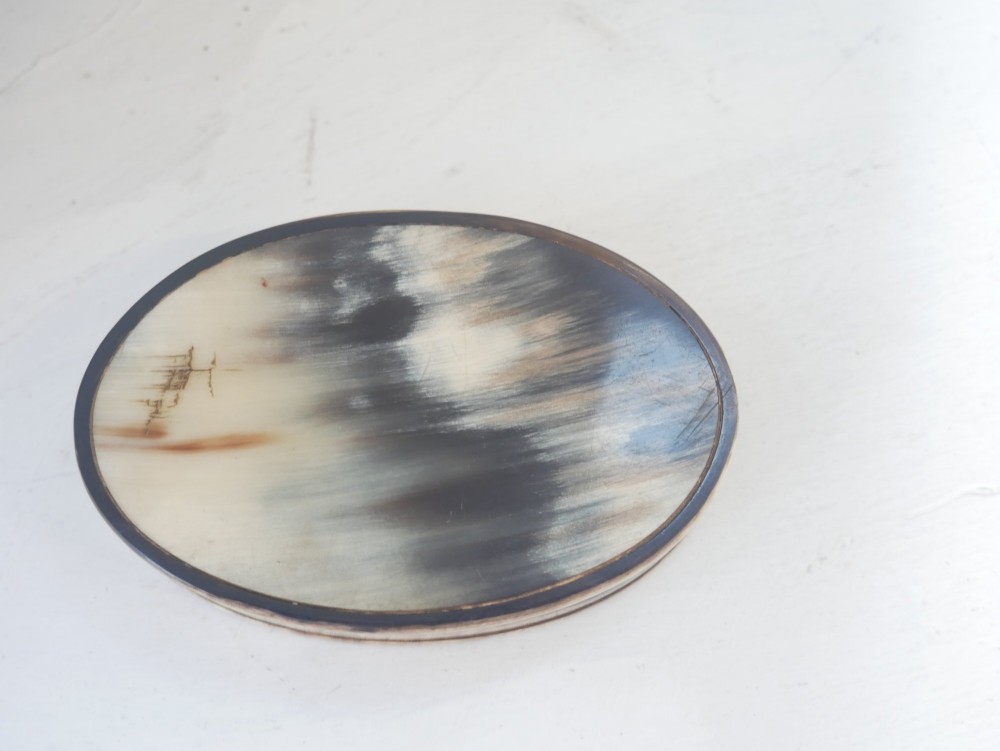 An oval antique snuff box crafted from polished natural horn showing variegated cream, amber, and dark brown mottling. View IV