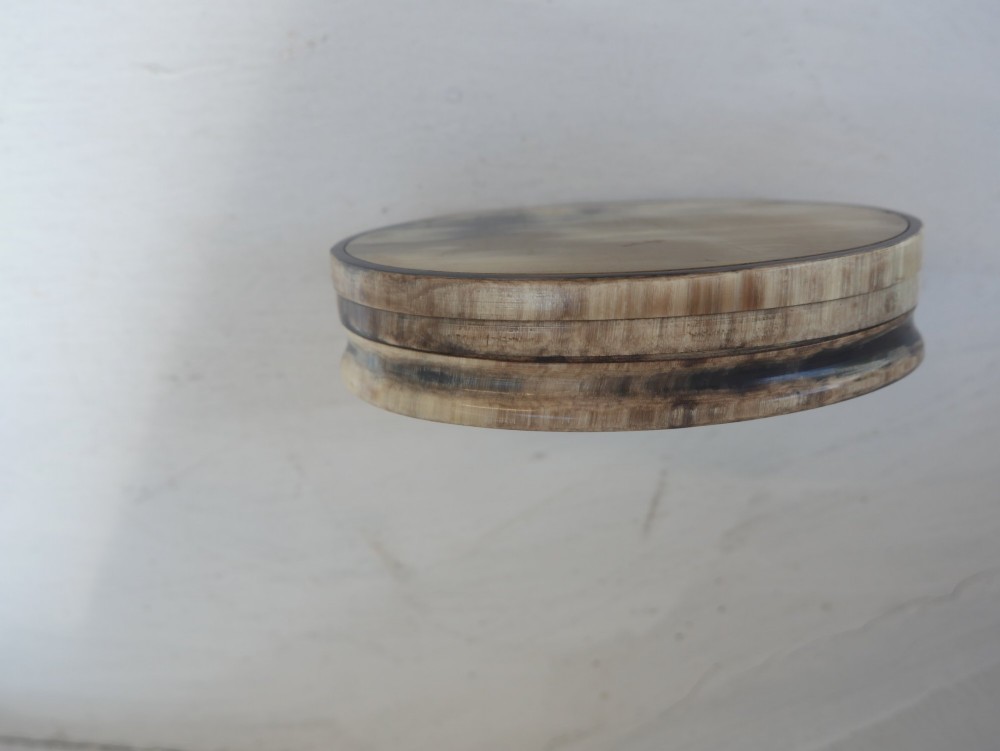 An oval antique snuff box crafted from polished natural horn showing variegated cream, amber, and dark brown mottling. View V