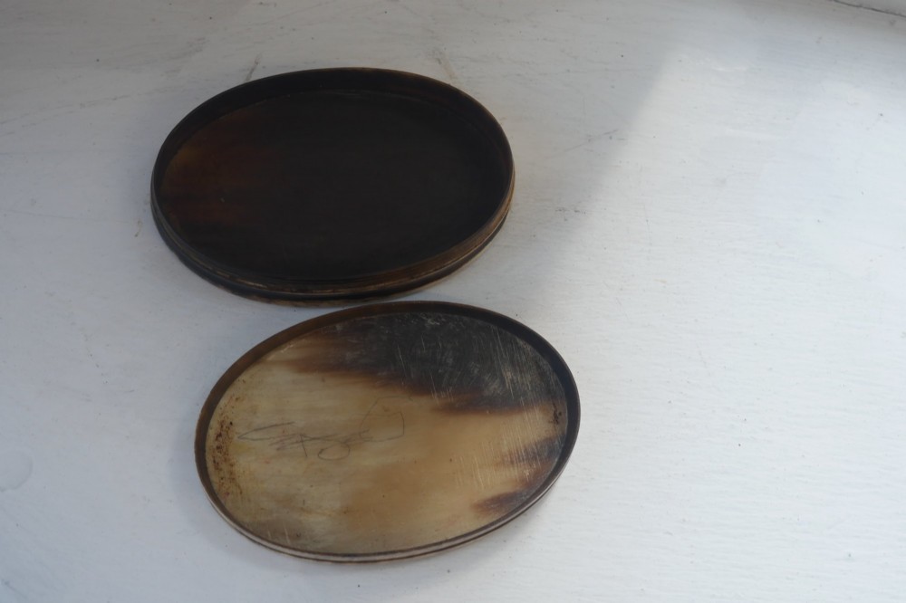 An oval antique snuff box crafted from polished natural horn showing variegated cream, amber, and dark brown mottling. View VI