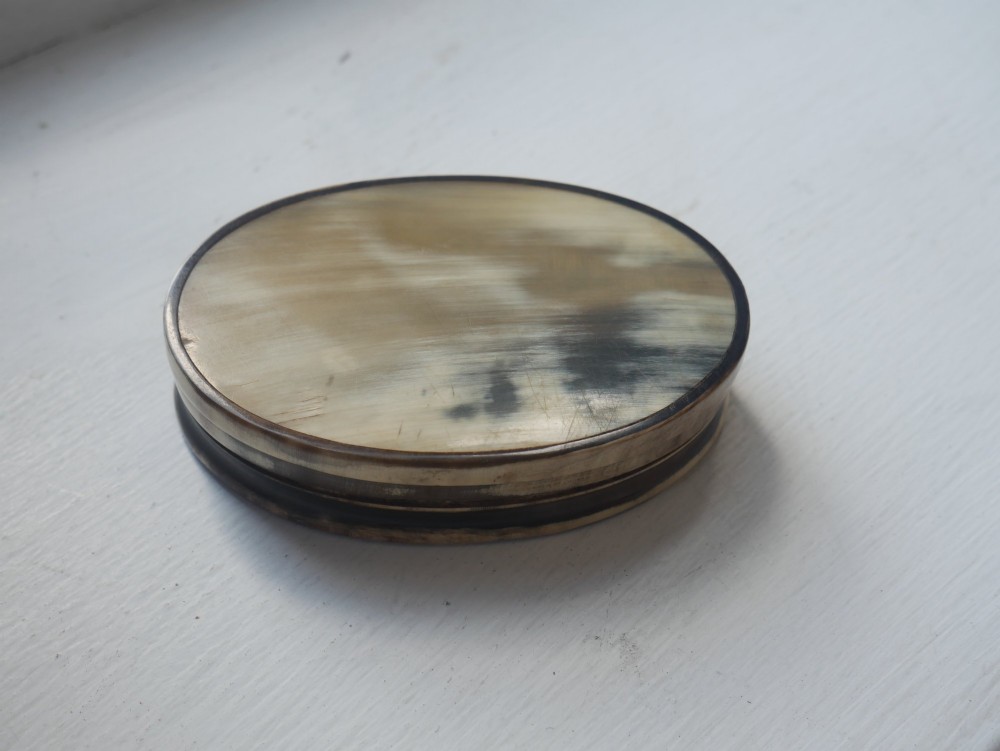An oval antique snuff box crafted from polished natural horn showing variegated cream, amber, and dark brown mottling. View VII