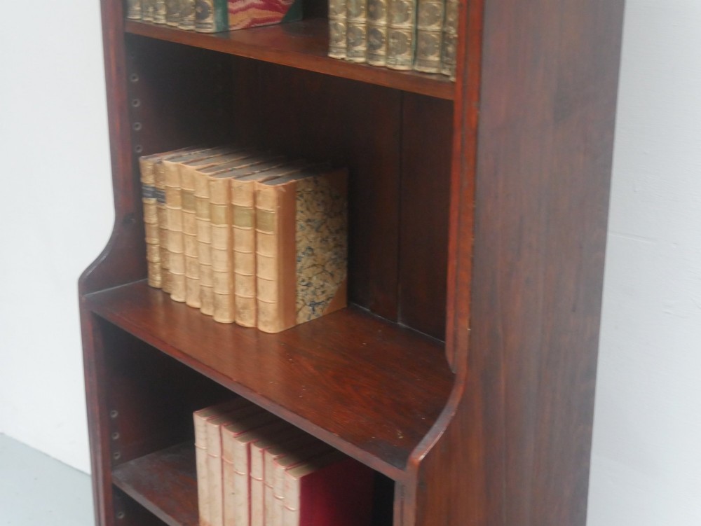 A tall, narrow 1920s dark oak open bookcase featuring five shelves and turned bun feet. View II