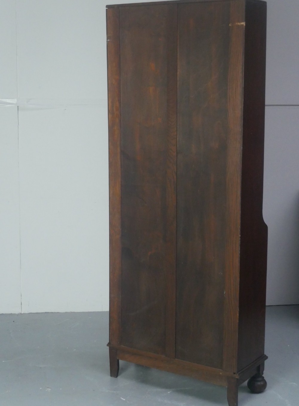A tall, narrow 1920s dark oak open bookcase featuring five shelves and turned bun feet. View IX