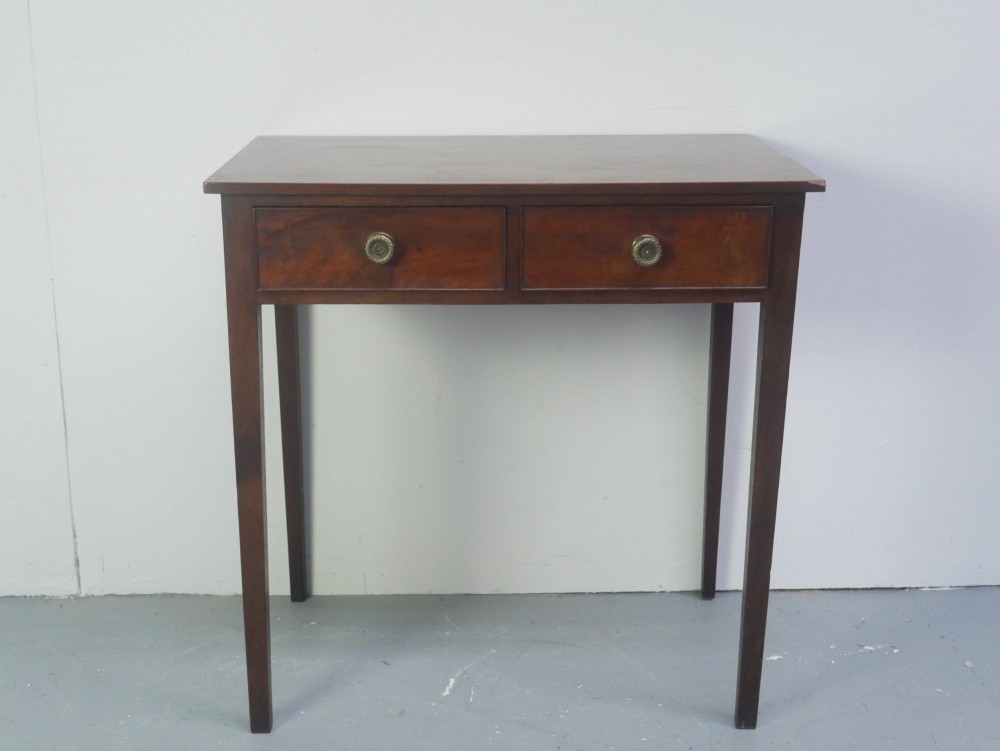 A rectangular Georgian mahogany side table with two frieze drawers, circular brass knobs, and four straight tapered legs.