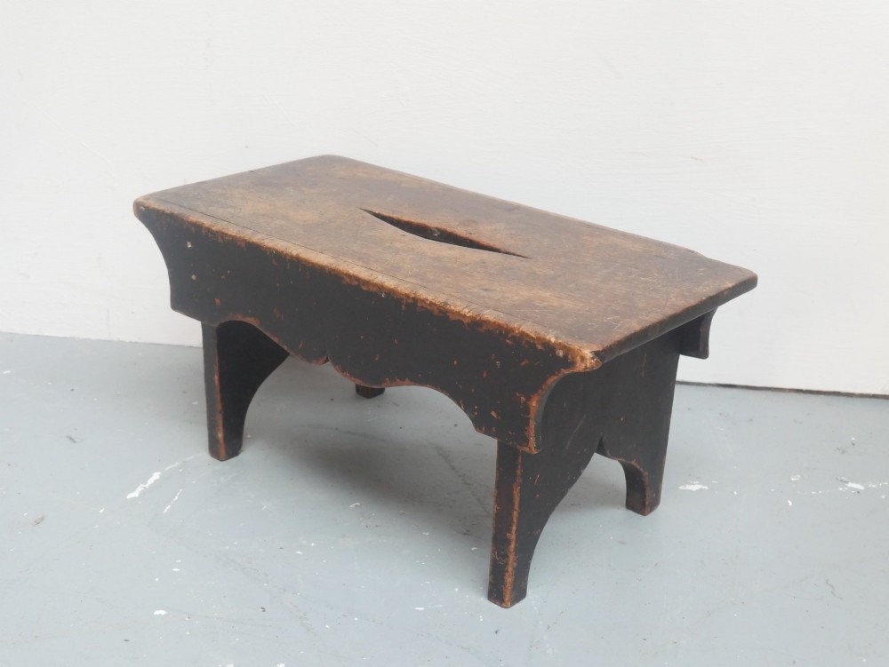 A small antique Scottish vernacular creepie stool constructed from dark patinated wood with a central handhole aperture and shaped board legs. View II