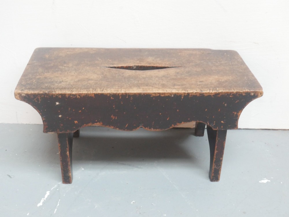 A small antique Scottish vernacular creepie stool constructed from dark patinated wood with a central handhole aperture and shaped board legs. View VI