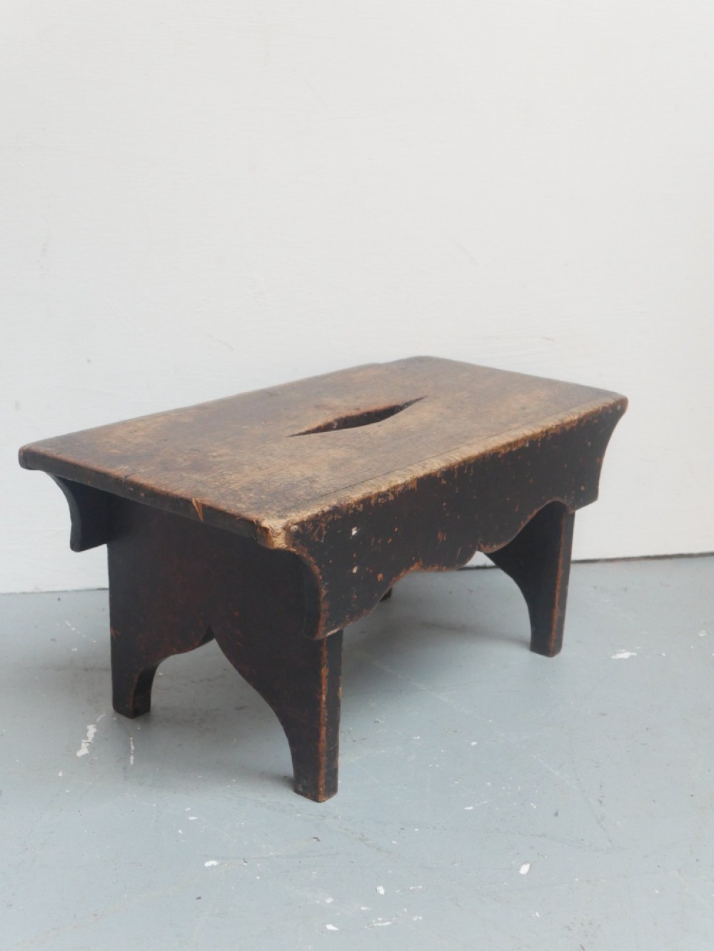 A small antique Scottish vernacular creepie stool constructed from dark patinated wood with a central handhole aperture and shaped board legs. View VIII