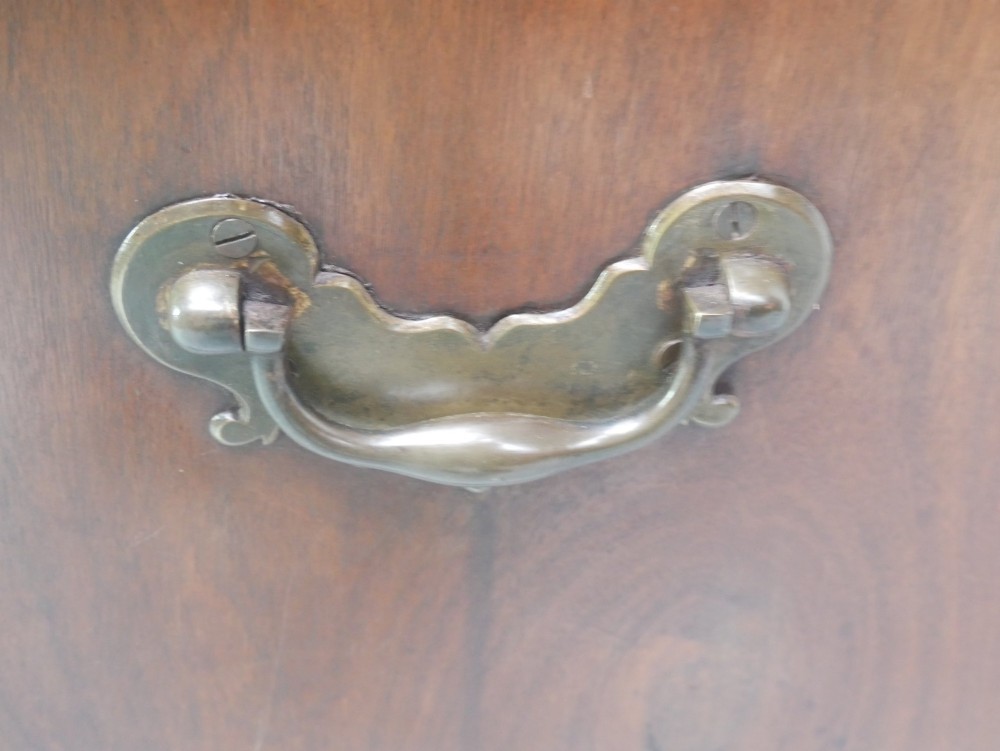 A low Georgian mahogany linen cupboard featuring two shaped panel doors, brass keyhole escutcheons, side handles, and bracket feet. View VI