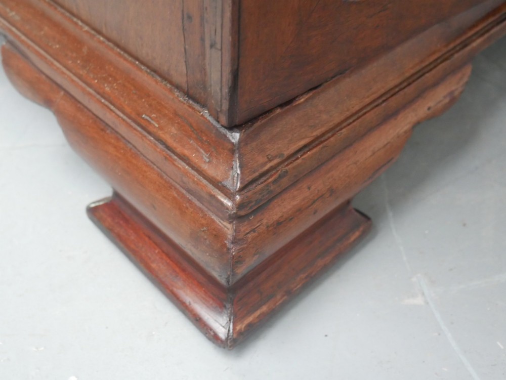 A low Georgian mahogany linen cupboard featuring two shaped panel doors, brass keyhole escutcheons, side handles, and bracket feet. View VII