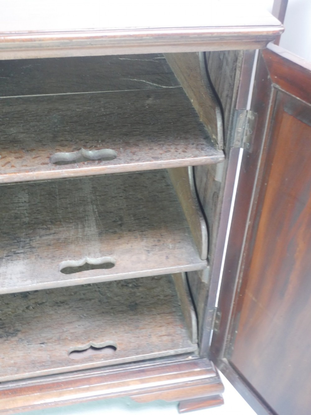 A low Georgian mahogany linen cupboard featuring two shaped panel doors, brass keyhole escutcheons, side handles, and bracket feet. View IX