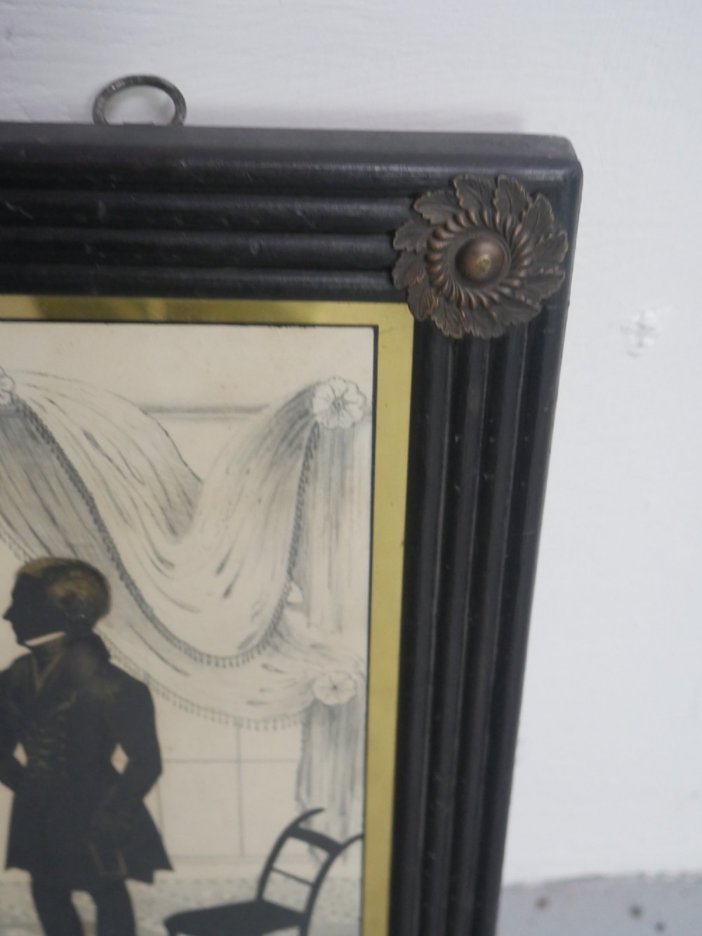 A framed antique Regency silhouette depicting a family group in a decorative interior setting set within an ebonised moulded frame with brass slip. View IV