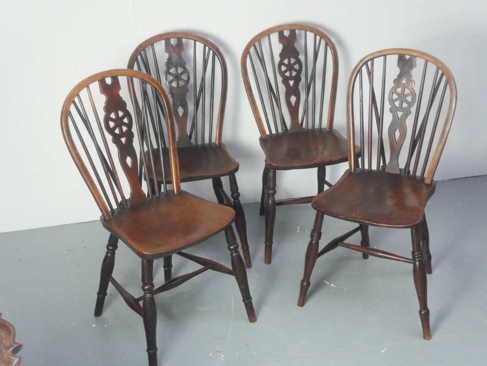 A set of four 19th-century dark wooden Windsor dining chairs featuring pierced wheelback central splats and turned legs.