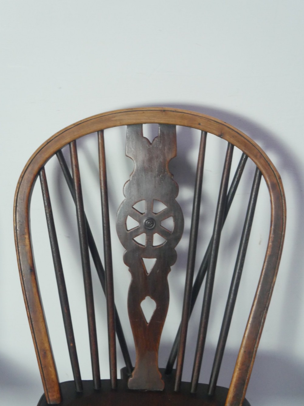 A set of four 19th-century dark wooden Windsor dining chairs featuring pierced wheelback central splats and turned legs. View II