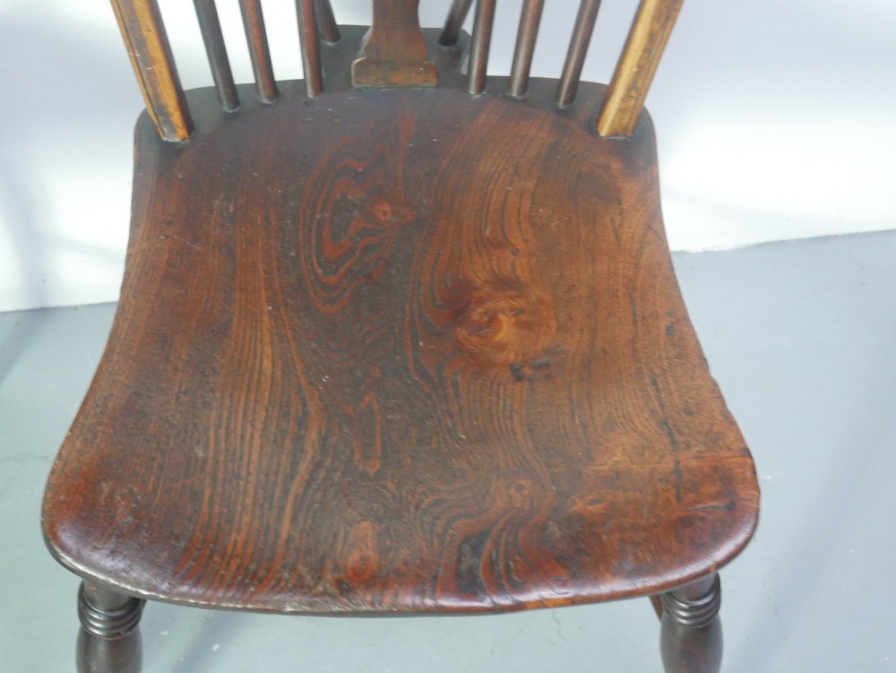 A set of four 19th-century dark wooden Windsor dining chairs featuring pierced wheelback central splats and turned legs. View III