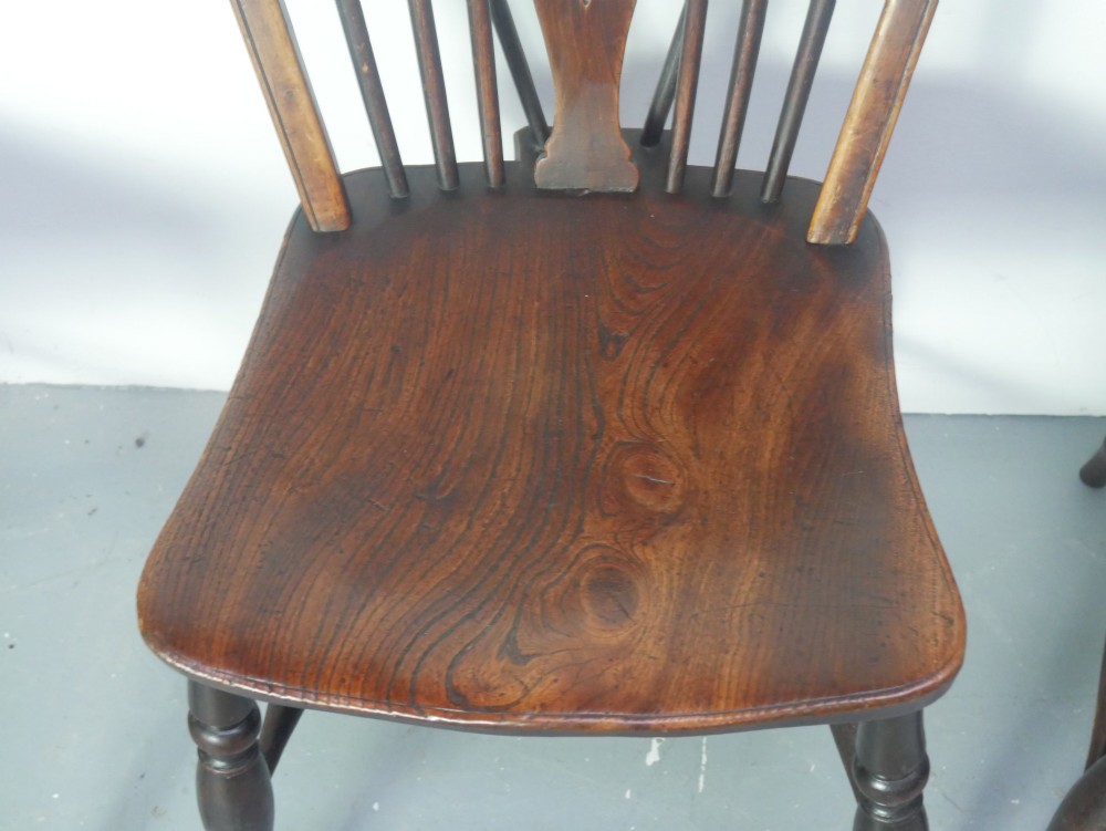 A set of four 19th-century dark wooden Windsor dining chairs featuring pierced wheelback central splats and turned legs. View IV