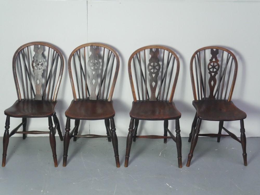 A set of four 19th-century dark wooden Windsor dining chairs featuring pierced wheelback central splats and turned legs. View VIII