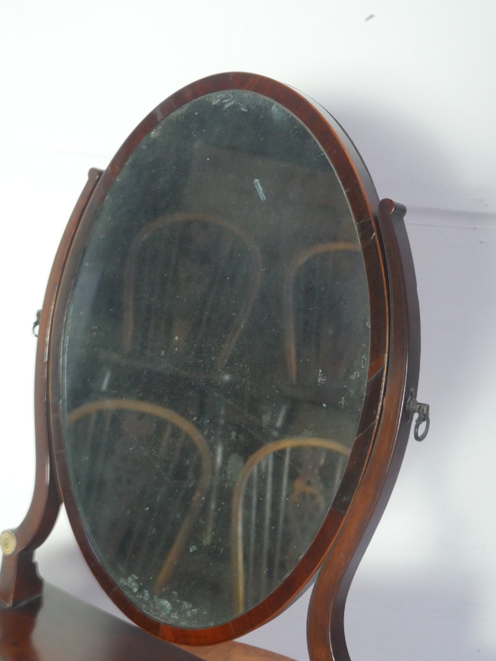 An antique Georgian mahogany dressing mirror with an oval adjustable glass supported on curved arms above a serpentine three-drawer base. View III