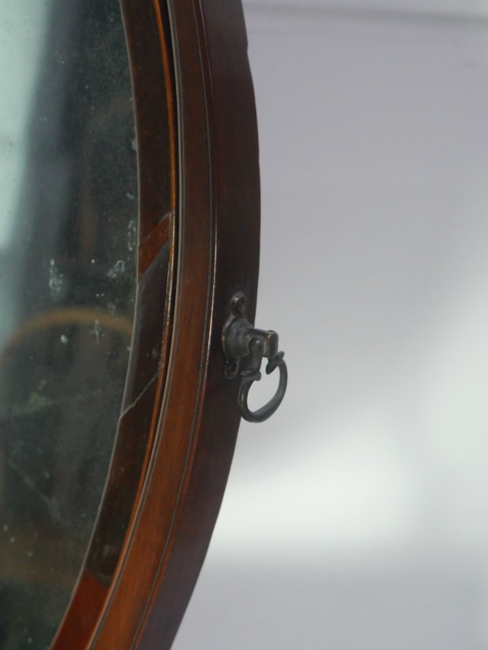 An antique Georgian mahogany dressing mirror with an oval adjustable glass supported on curved arms above a serpentine three-drawer base. View IV