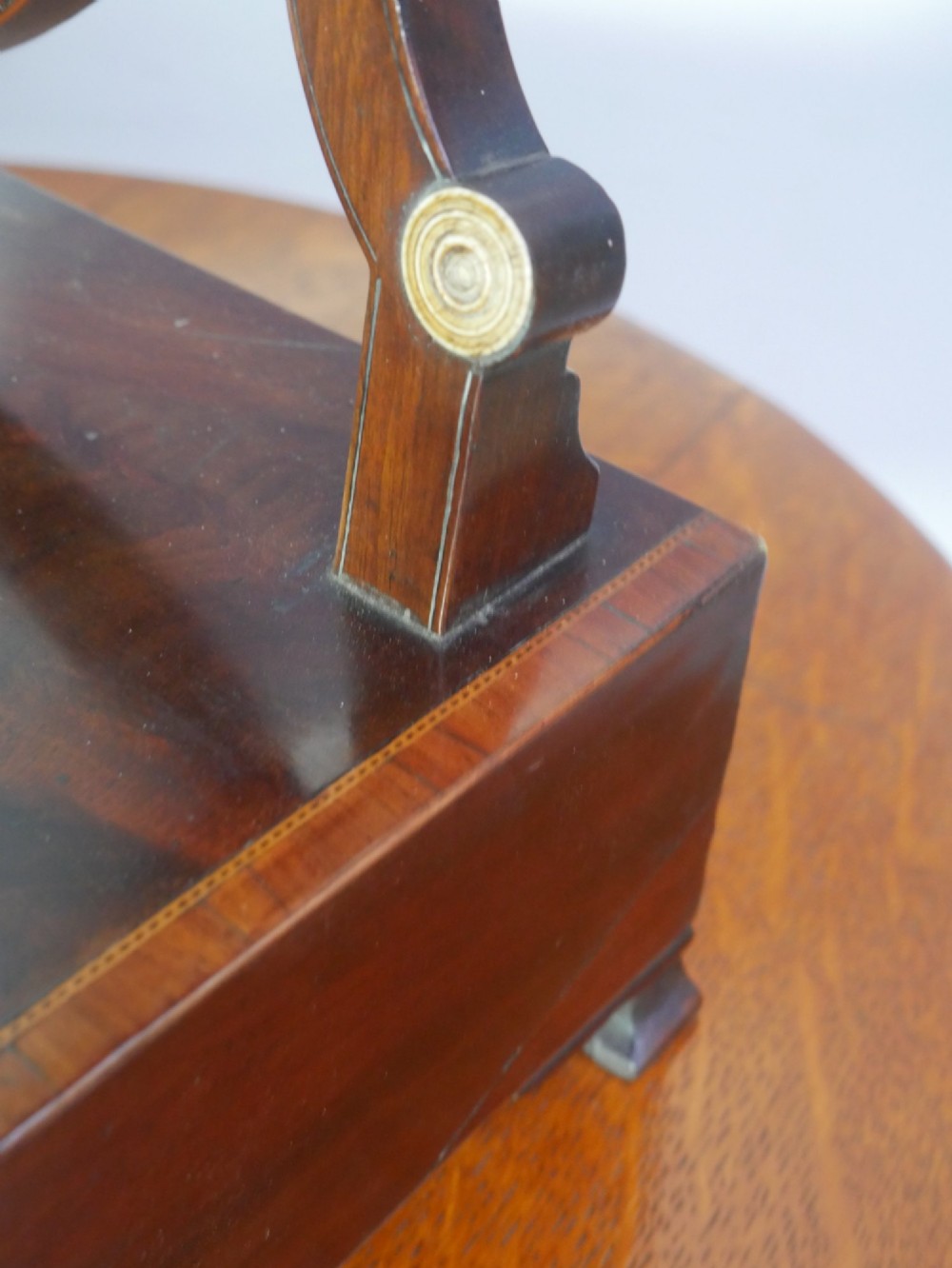 An antique Georgian mahogany dressing mirror with an oval adjustable glass supported on curved arms above a serpentine three-drawer base. View V