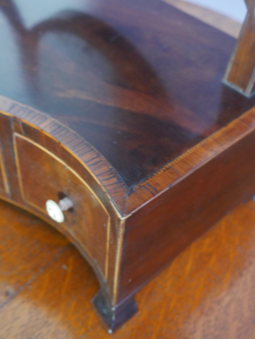 An antique Georgian mahogany dressing mirror with an oval adjustable glass supported on curved arms above a serpentine three-drawer base. View VI