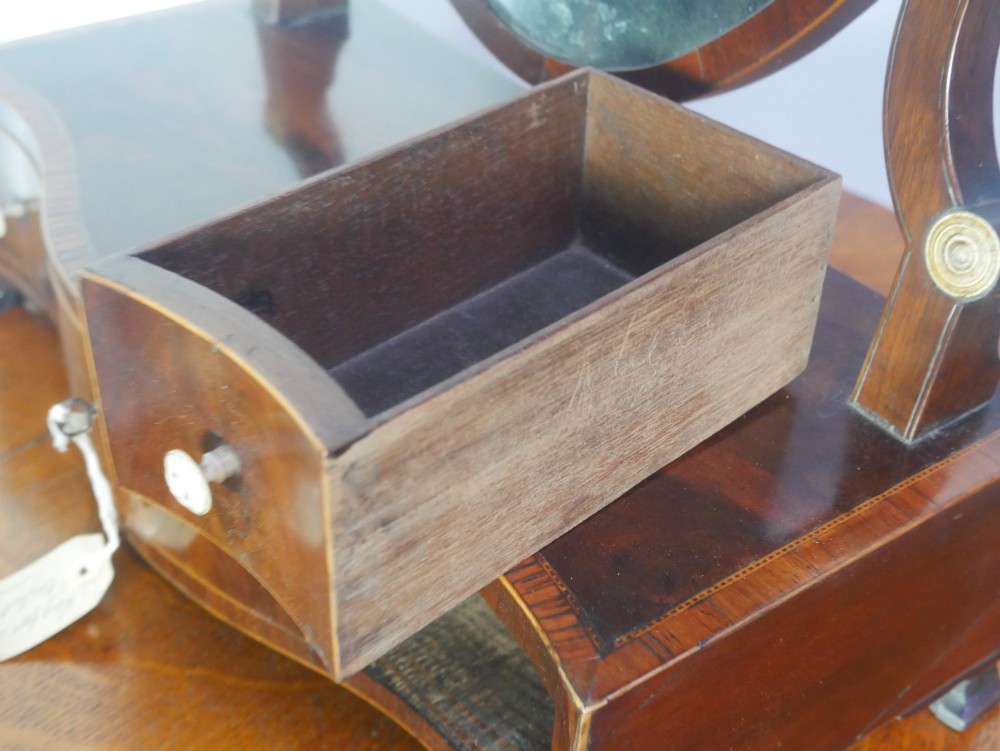 An antique Georgian mahogany dressing mirror with an oval adjustable glass supported on curved arms above a serpentine three-drawer base. View VIII