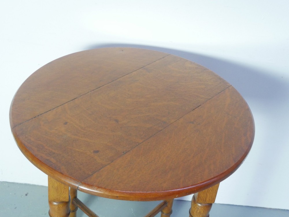 A round 1920s oak lamp table featuring turned legs supported by an X-frame stretcher. View II