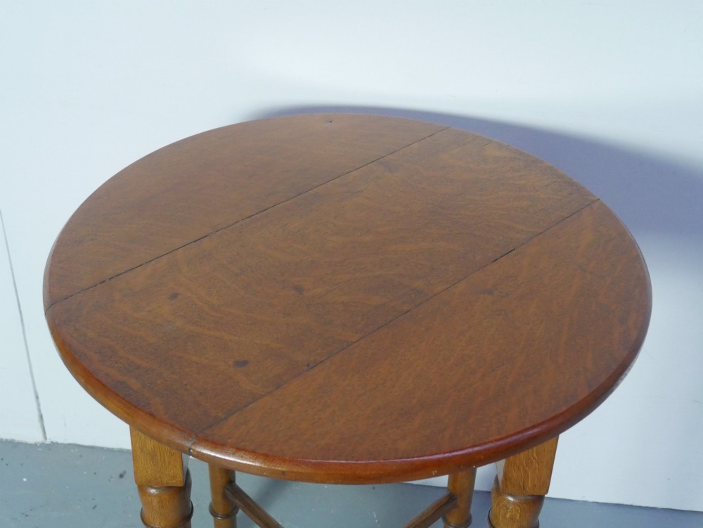 A round 1920s oak lamp table featuring turned legs supported by an X-frame stretcher. View V