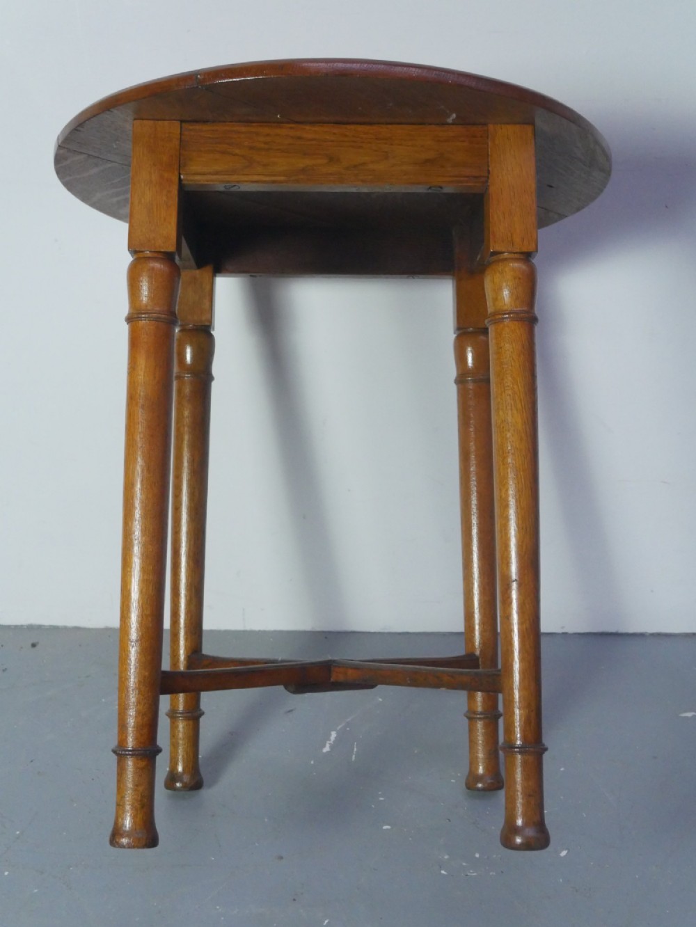 A round 1920s oak lamp table featuring turned legs supported by an X-frame stretcher. View VIII