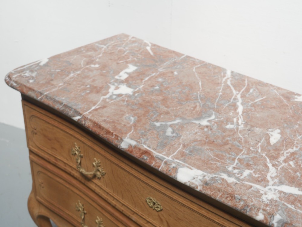 A French provincial style oak chest of drawers featuring two moulded panel drawers, ornate cast brass handles, cabriole legs, and a red-toned marble top. View II