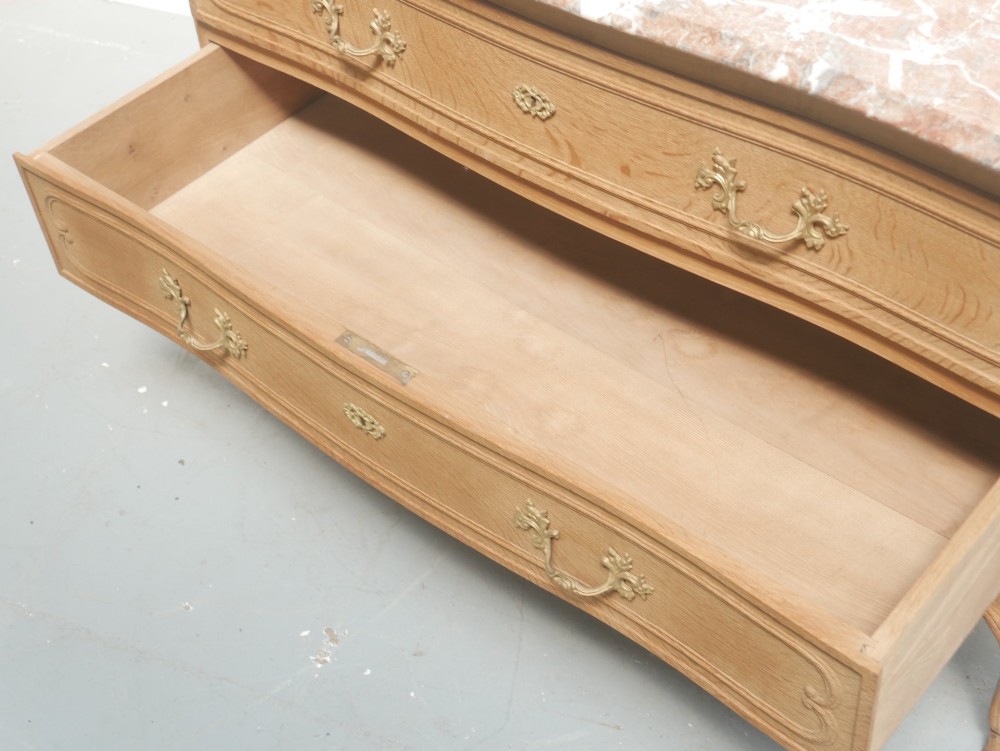 A French provincial style oak chest of drawers featuring two moulded panel drawers, ornate cast brass handles, cabriole legs, and a red-toned marble top. View III