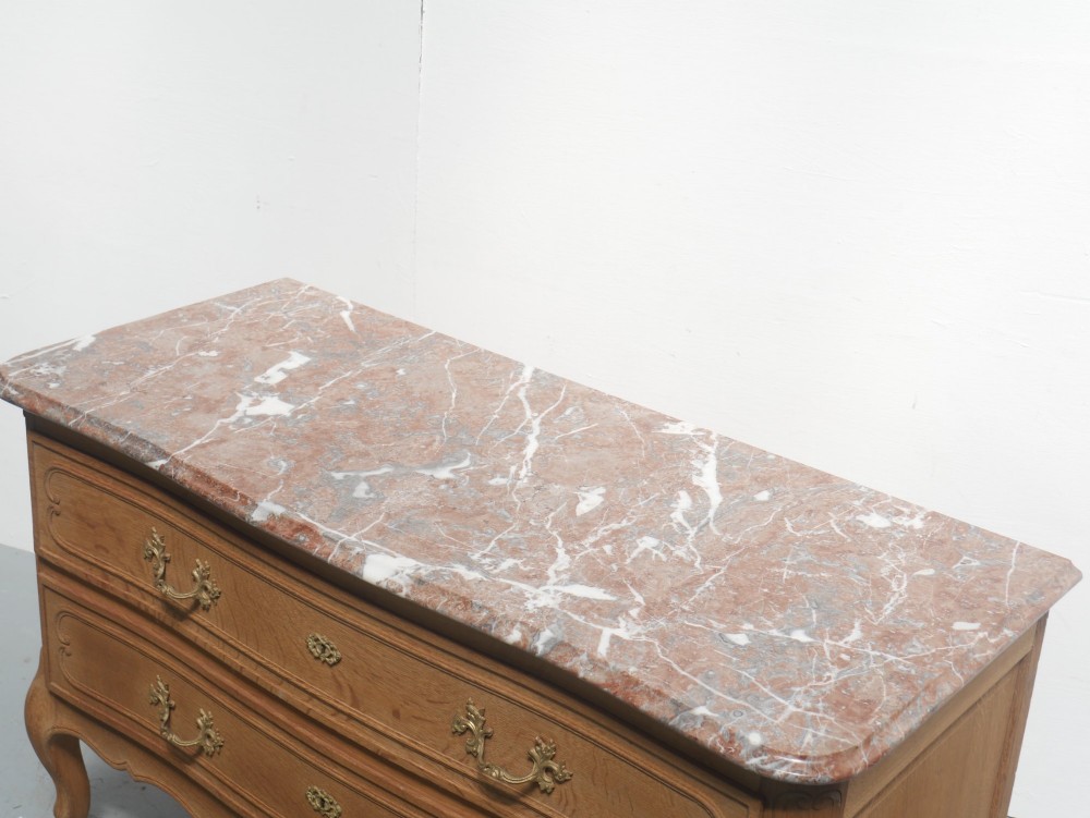 A French provincial style oak chest of drawers featuring two moulded panel drawers, ornate cast brass handles, cabriole legs, and a red-toned marble top. View IV